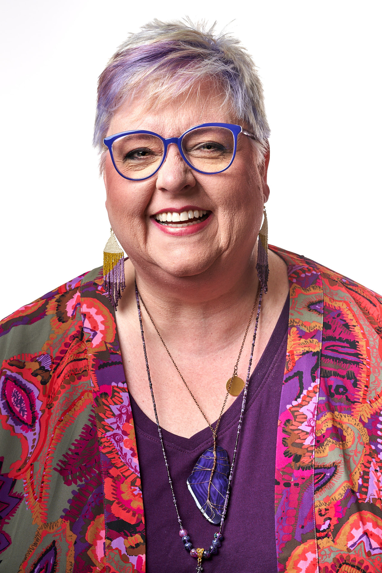 Terrie Hellard-Brown smiling, wearing purple and a colorful patterned jacket